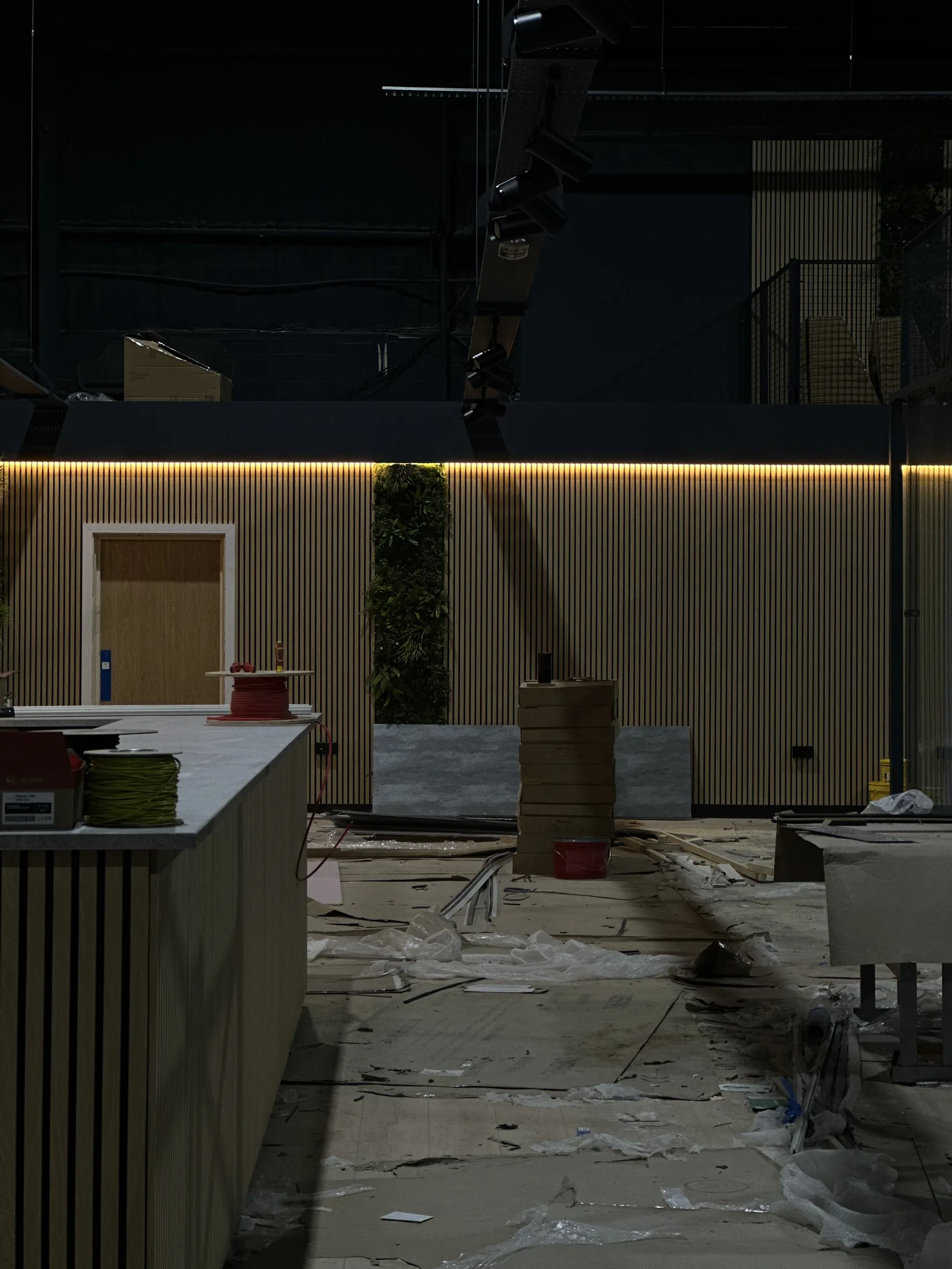 Warm linear lighting above timber wall panels during a fit-out